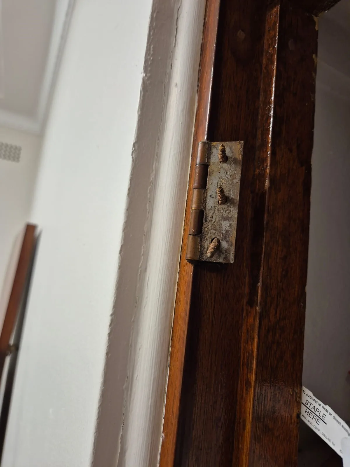 Aged hinge and fixings on a timber door frame before repair assessment