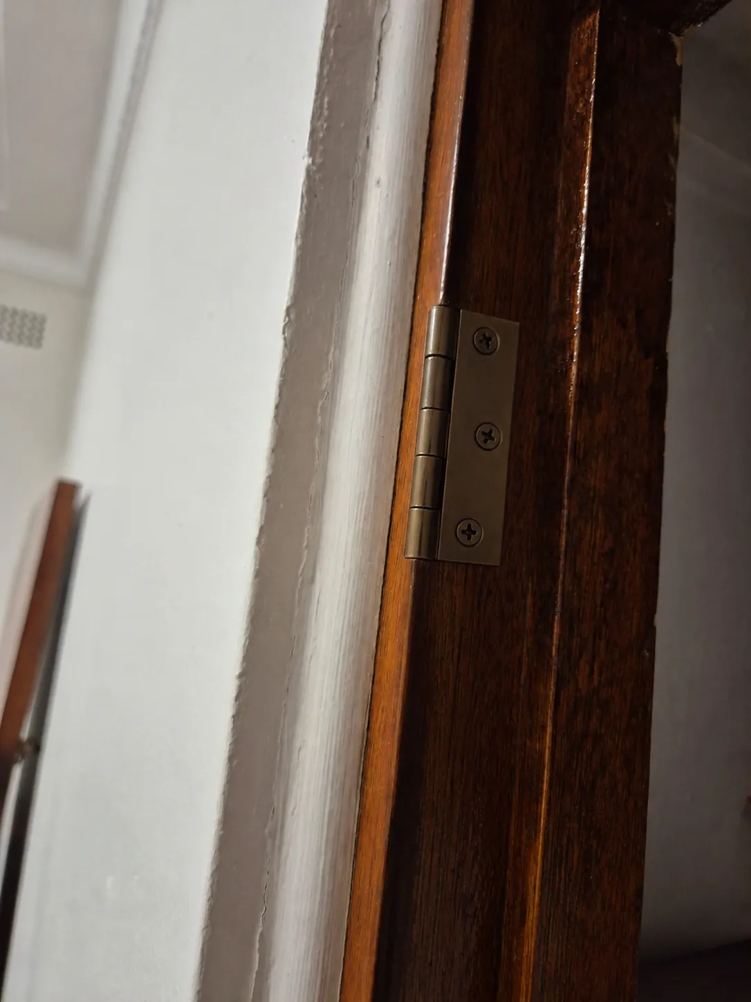 Illustrated completed condition of renewed hinge fixings on the timber door frame